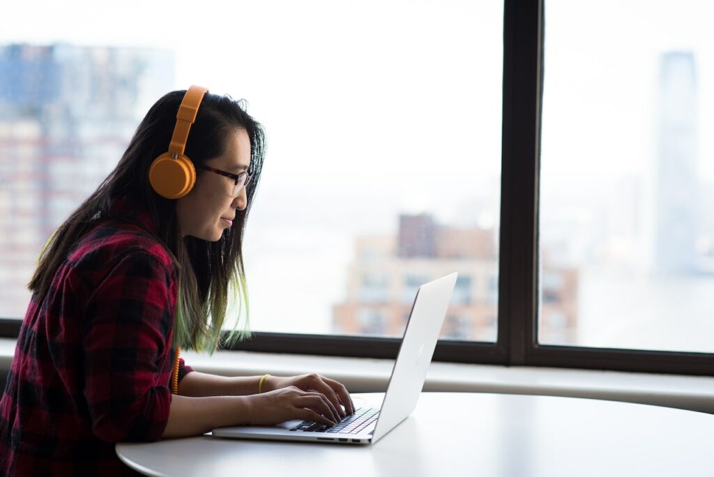 Woman wearing orange headphones and working on computer