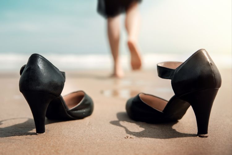 business woman taking her shows off on a beach