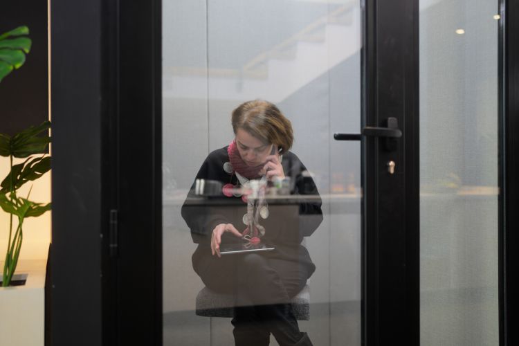 Woman holding a phone to her ear and a tablet on her knee